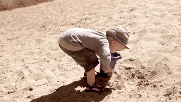 Mały chłopiec gra w piaszczystej plaży — Wideo stockowe