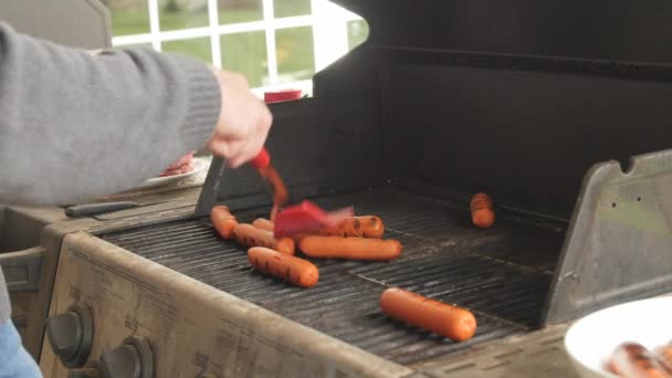 Człowiek, gotowanie hamburgery i Hot dogi na grilla — Wideo stockowe