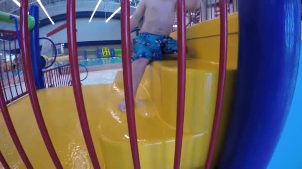 Мальчик играет в закрытом бассейне аквапарка — стоковое видео