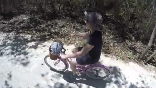 Una mujer montando su bicicleta en un camino de tierra — Vídeo de stock