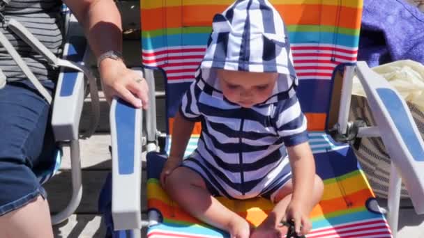 Menino brincando na cadeira de praia — Vídeo de Stock