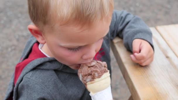 Мальчик ест мороженое в конусе — стоковое видео