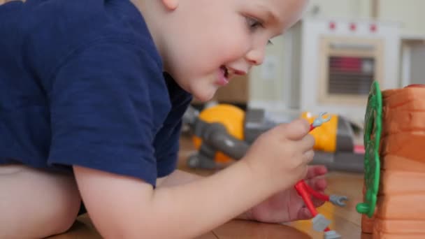 Niño jugando con robot de juguete en el suelo — Vídeos de Stock
