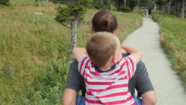 Jungen auf dem Rücken der Mütter, während sie wandert — Stockvideo