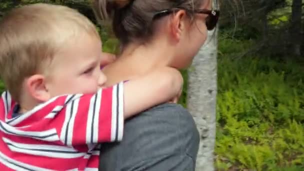 Meninos se sentam nos ombros das mães enquanto ela caminha — Vídeo de Stock