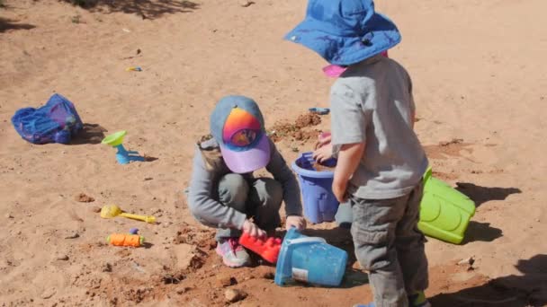 Niños jugando en arena con cubos y palas — Vídeo de stock