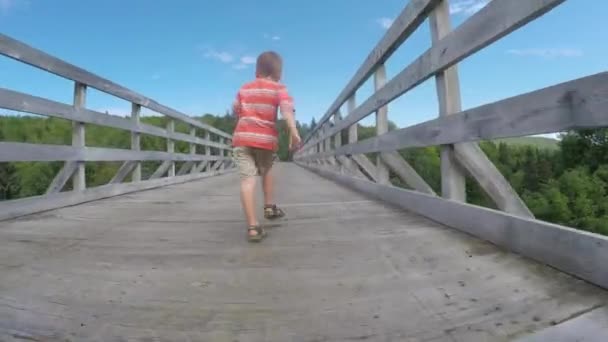 Menino correndo em uma ponte de madeira — Vídeo de Stock