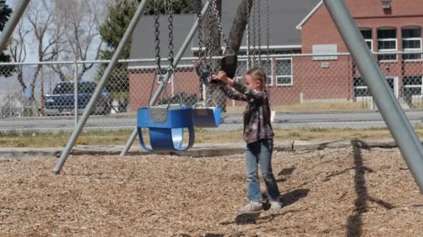 Chica jugando con columpios en el parque público — Vídeo de stock