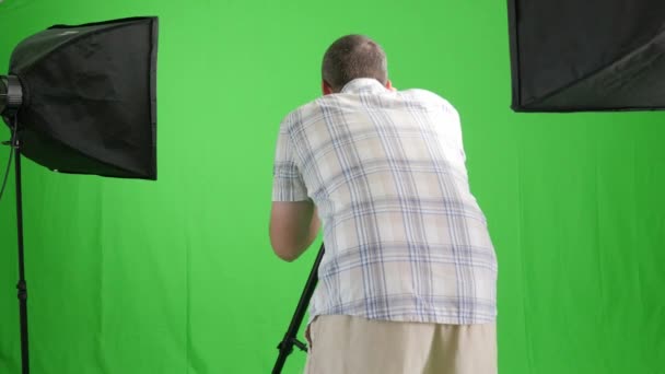 Fotograaf in studio op groen — Stockvideo