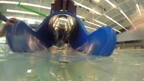 Мальчик спускается с водной горки в бассейне — стоковое видео