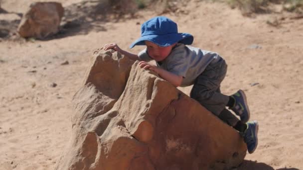 砂漠の岩の小さな男の子のクライミング — ストック動画