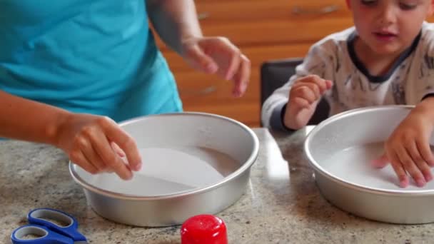 Madre hace un pastel con sus hijos pequeños — Vídeos de Stock