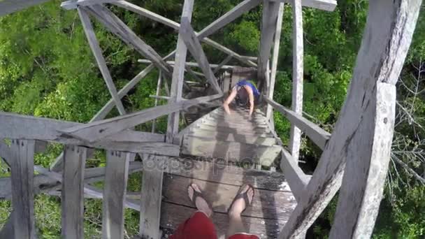 Άνθρωποι αναρρίχηση ένα ξύλινο πύργο πάνω από το δάσος — Αρχείο Βίντεο