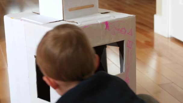 Маленький мальчик раскрашивает самодельного робота — стоковое видео