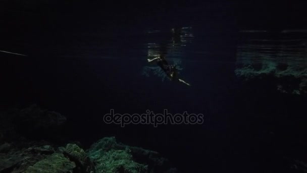 Junge Frau schwimmt in dunkler Cenote — Stockvideo