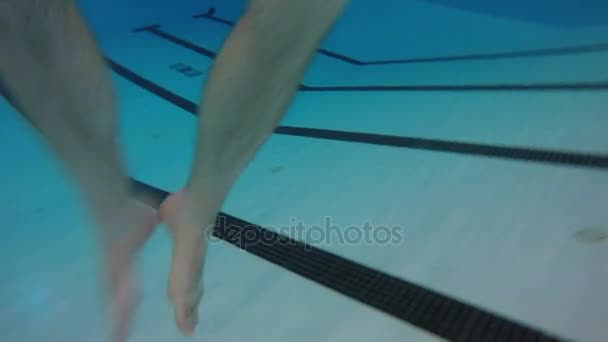 Mann tritt mit Beinen auf Wasser am Pool — Stockvideo