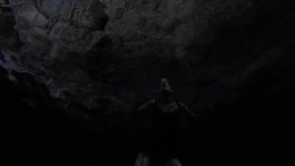 Bonita mujer nadando en oscuro cenote — Vídeo de stock