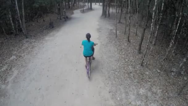 Mujer montando una bicicleta en un camino de tierra — Vídeos de Stock