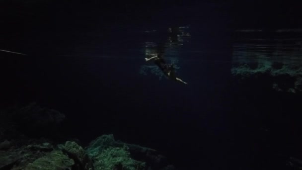 在黑暗岩游泳的年轻女子的水下射击 — 图库视频影像