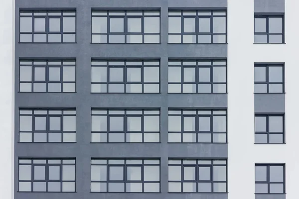 Koyu gri cephe bina gri büyük pencereler ile. Büyük beyaz çizgiler. Apartman. Aile. Emlak