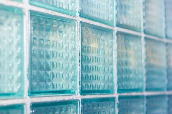 Decorative and glossy glass block window in blue as a texture or for background. The wall. Geometric background.