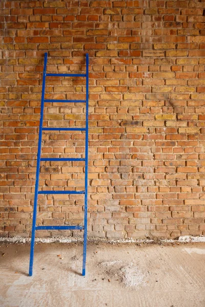 The blue staircase leaned against the wall of red brick