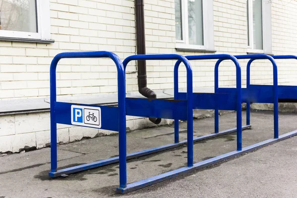 A metal bicycle park of blue color that stands in the city near