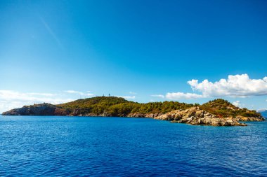 Kayalık sahil ile Ege Denizi ağaçlarda. Güzel beyaz bulutlar
