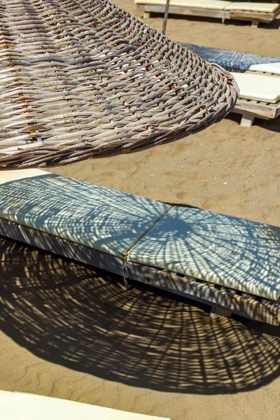 Ein Sonnenschirm aus Stroh mit Liegestühlen auf dem Sand — Stockfoto