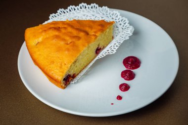 Vişneli pasta dilimi kırmızı sos ile beyaz bir plaka üzerinde