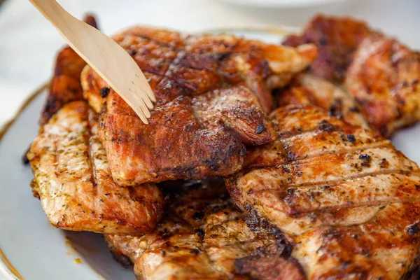 Grilled steak at the campsite lies in a white plate on the table