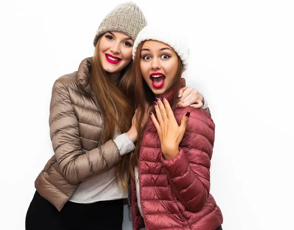 Indoor fashion lifestyle portrait of pretty teen happy friends girls standing together,having fun.Showing signs with hands.Two pretty cuter teenagers shares secrets, gossip. Surprise face, emotions. — Stock Photo, Image