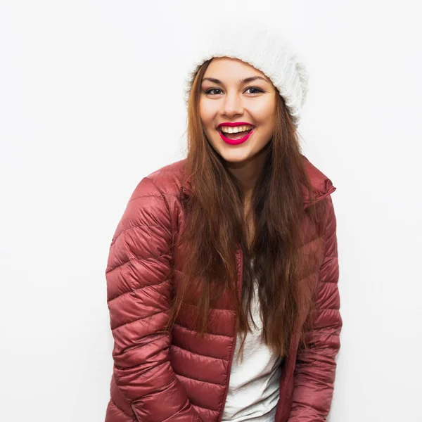 Beauty portrait of a young beautiful girl with long dark straight hair wearing white color warm hat and trendy pink coat. Young brunette hipster girl having fun,smiling and looking at camera. — Stock Photo, Image