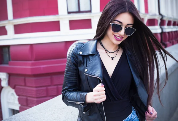 Estilo de vida al aire libre retrato de moda de la joven mujer hipster elegante caminando por la calle, usando ropa de moda lindo. Mujer joven con el pelo largo y oscuro sonriendo a la cámara en la ciudad en el fondo bulding ciudad . — Foto de Stock