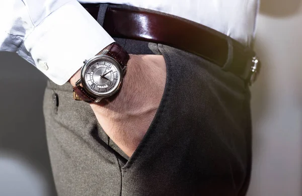 Close-up mode beeld van luxe horloge aan pols van man.body detail van een zakenman. Iemands hand in een grijs shirt met Manchetknopen in een broek zak close-up. Tonale correctie. — Stockfoto