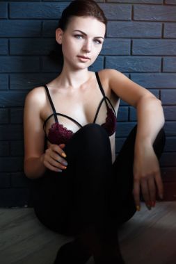 Güzel genç kadın portre. Genç güzel seksi kadın yatak odasında poz baştan çıkarıcı kadın iç çamaşırı. Sutyen, katta oturan genç modelinde portresi. Siyah külot ile esmer kız