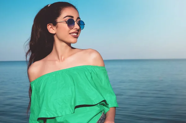 Menina bonita em vestido verde sorrindo para a waterfront.Beautiful verão cabelo encaracolado menina na praia — Fotografia de Stock