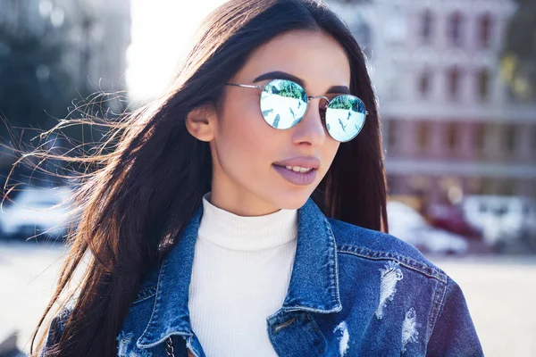 Chica Hipster con camiseta gris en blanco, jeans y mochila posando contra la pared de la calle áspera, ropa urbana minimalista style.Attractive mujer en jeans con pelo largo y oscuro —  Fotos de Stock