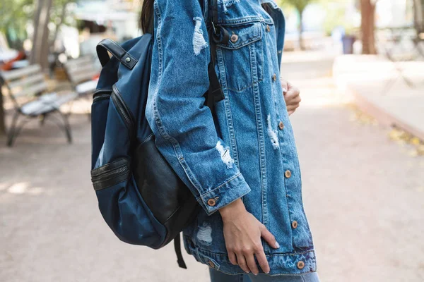 Trendy jonge vrouw in jeans, lange jeans jasje en handtas op de straten van de stad. Fashion.Stylish.Close beeld van mode details, jeans jasje, stijlvolle tas. — Stockfoto