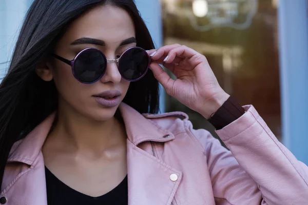 Estilo de vida al aire libre retrato de moda de la joven mujer hipster elegante caminando por la calle, usando ropa de moda lindo. Mujer joven con el pelo largo y oscuro sonriendo a la cámara en la ciudad en el fondo del edificio de la ciudad . —  Fotos de Stock