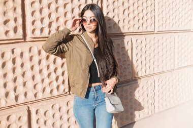 Moda Sonbahar Bahar gündelik kıyafeti şehirde yürüyüş şık kadın portre kapatın. Sokak style.young sokak arka planda haki bombardıman ceket, kot pantolon ve çanta, sonbahar moda trendi güzel kadın.