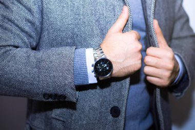 Moda aksesuarları üzerinde hands.wearing siyah ceket, çelik saatler, siyah yelek, gri yün ceket ile rahat bez elbiseli genç işadamı yakışıklı modeli adam portresi.