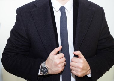 Moda aksesuarları hands.wearing siyah yün ceket, çelik saatler, beyaz gömlek ile rahat bez elbiseli genç işadamı yakışıklı modeli adam portresi.