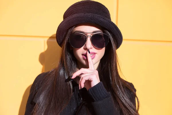 Shh! Women's secrets. Cropped shot of female with finger in mouth. Closeup portrait of young woman is showing a sign of silence
