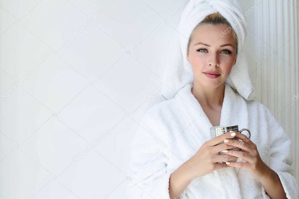 Portrait of beautiful girl in bathrobe with a cup of tea, home style relaxation concept blonde woman wearing bathrobe and towel on head after shower. Spa woman in bathrobe and turban