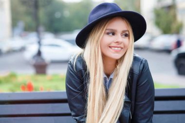 Yan açık havada bakarak gülümsemek olumlu çekici kız. Hayat mutlu şık genç kadının portresi. Bankta oturmuş.