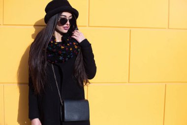 Güzellik moda portre. Sarı duvar arka plan üzerinde güzel ve genç birbayan. Duvar arka planı gülümseyen güneş gözlüğü şık genç kadın görüntüsünü kapatın. Güzel kadın modeli ile kopya alanı.