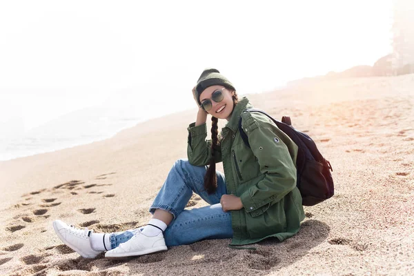 Tourist traveler sitting by ocean sea scape, hipster girl looking on nature horizon, relax holiday.Copy space.woman with backpack coming to ocean to make new photo and enjoy weekend.Stylish girl.