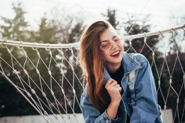 Bahar açık moda parlak yapmak eğlenceli ve sevimli gülümseyen, giyiyor rahat kot elbise, kentsel arka plan, parlak renkler kadar genç esmer güzel kadın portresi. Güneşli bir gün, kopya alanı.