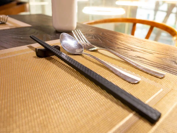 Ahşap yemek çubuğu, gümüş kaşık ve masa örtüsü üzerinde yaşayan insanlar.